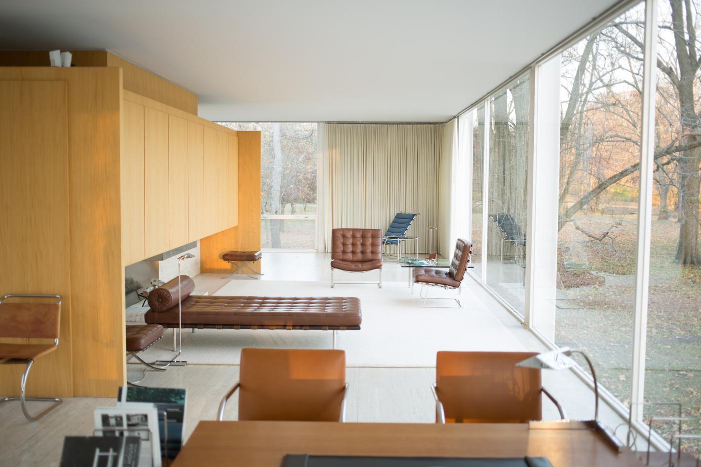 Minimal glass-walled interior with wood cabinetry and furniture